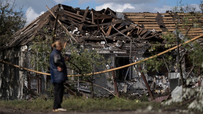 Žena stojí pred zničeným domom po ruskom raketovom útoku v meste Sloviansk.