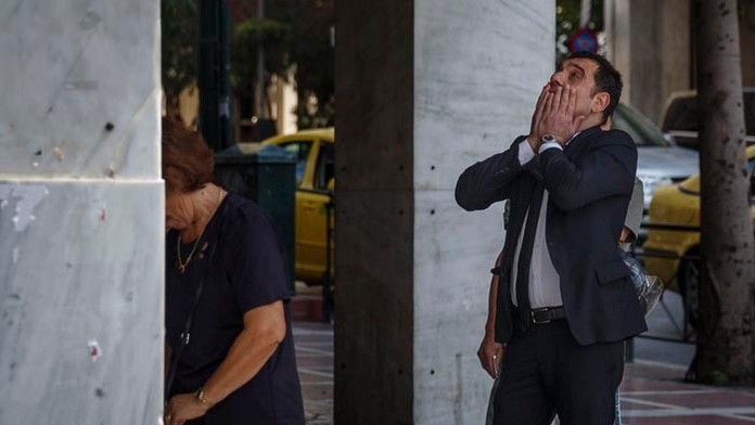 Ľudia stoja v rade pred bankomatom v gréckom meste Solún.