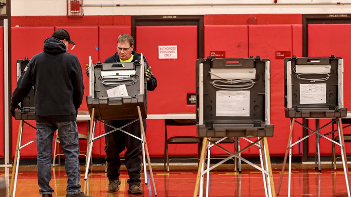 Zamestnanci rozkladajú hlasovacie boxy v miestnej strednej škole, v ktorej zriaďujú volebnú miestnosť počas príprav na hlasovanie deň pred prezidentskými voľbami v USA,