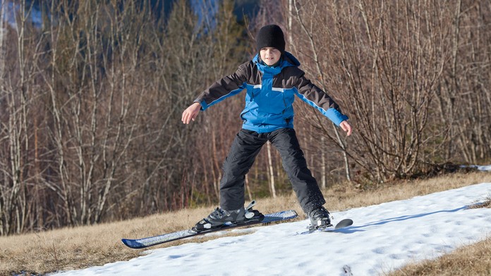 Chlapec na lyžiach po tráve