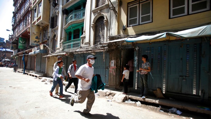 Muži utekajú pár sekúnd po tom, čo Nepál zasiahlo druhé zemetrasenie. 12. mája