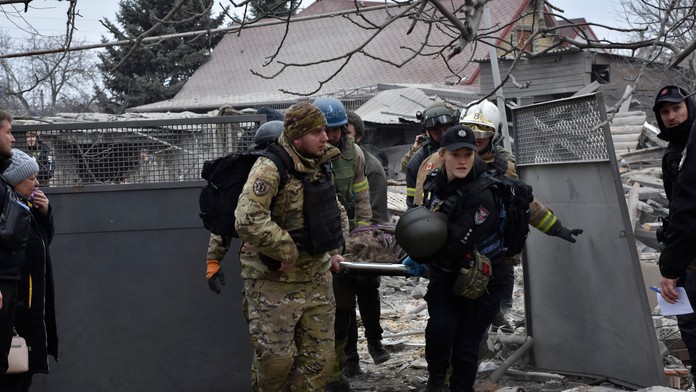 Ukrajinskí záchranári a vojaci nesú telo obyvateľa zabitého pri masívnom ruskom leteckom útoku v Záporoží na Ukrajine.