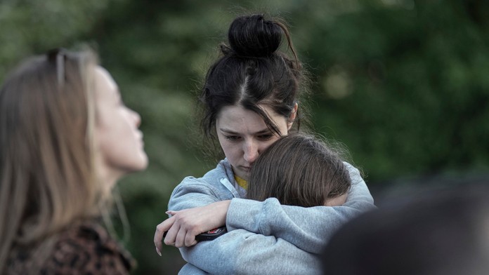 Evakuovaní pred zničenou bytovkou na Ukrajine.