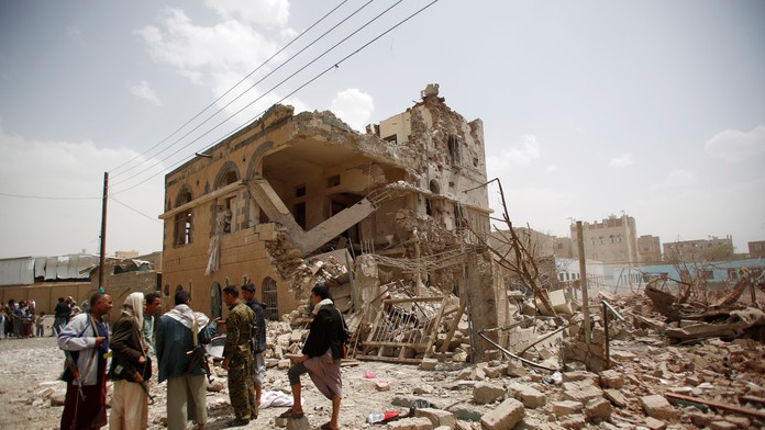 Húsíovia sa zhromažďujú pred zničeným domom po leteckom útoku saudsko-arabských vzdušných síl v Saná.jpg