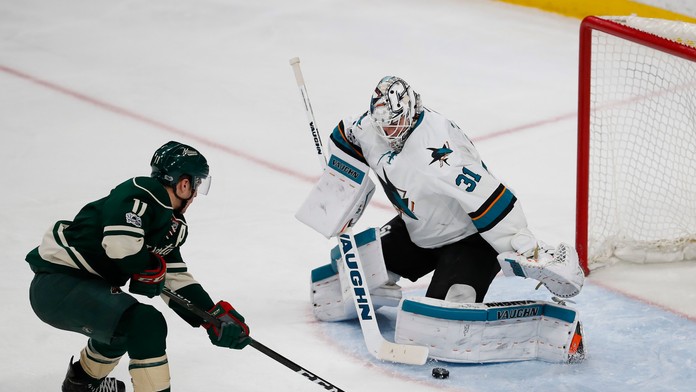 Gólman San Jose Martin Jones (vpravo) čelí Zachovi Parisemu z Minnesoty v dueli NHL.