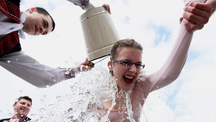 Mládenci v ľudových krojoch z obce Selec neďaleko Trenčína oblievajú dievča na Veľkončný pondelok.