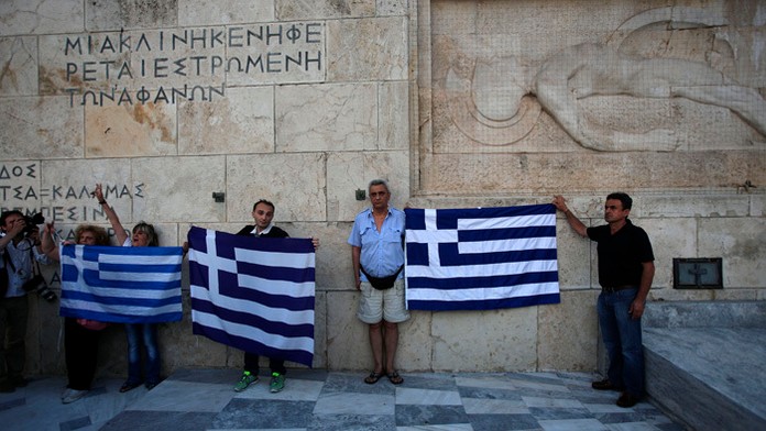 Grécki demonštranti proti úsporným opatreniam držia grécke zástavy počas protestného zhromaždenia proti vládnej dohode s veriteľ