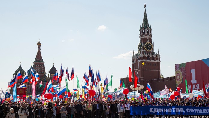 Rusi mávajú zástavami a skandujú počas prvomájových osláv na Červenom námestí v Moskve.