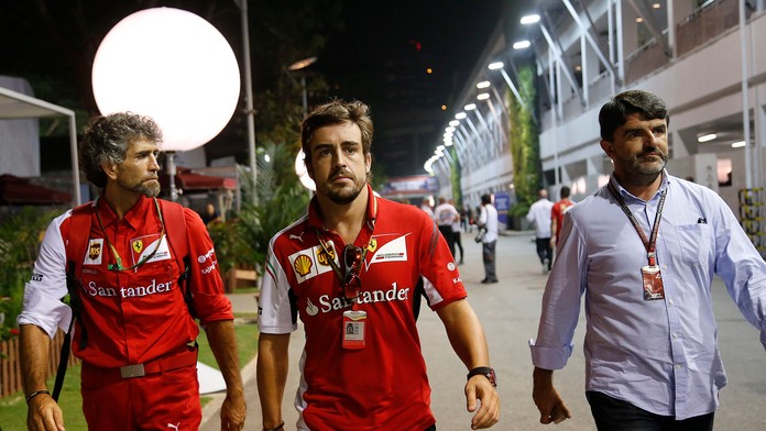 Španielsky pilot formuly 1 Fernando Alonso (uprostred) z tímu Ferrari v sprievode tímových kolegov  v Singapure.