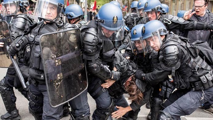 Poriadková polícia odvádza zadržaného demonštranta počas protestu proti plánovaným reformám.