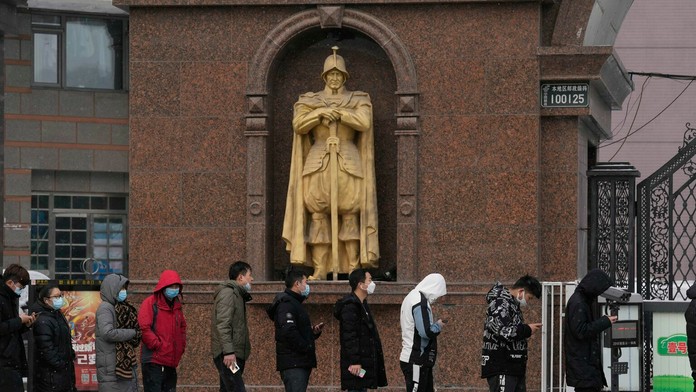 Zamestnanci gastro prevádzok v Pekingu stoja v rade na covid testy.
