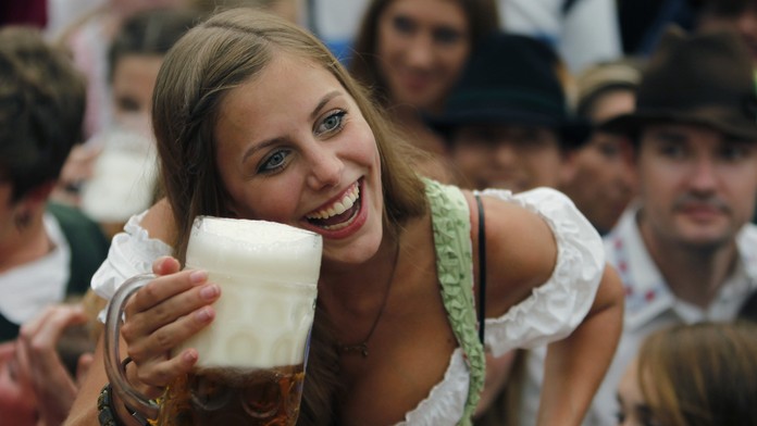 Mladá žena v kroji dvíha pohár piva po oficiálnom otvorení Októberfestu 2011.