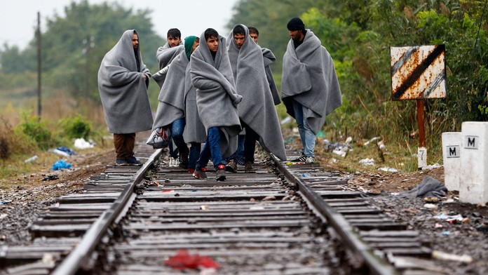 Migranti a utečenci kráčajú po koľajniciach po prekročení srbsko-maďarskej hranici pri maďarskej obci Röszke.