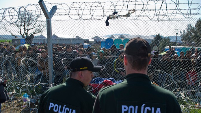 Na snímke migranti na gréckej strane hranice a slovenskí policajti. 