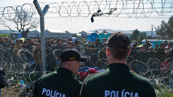 Na snímke migranti na gréckej strane hranice a slovenskí policajti. 