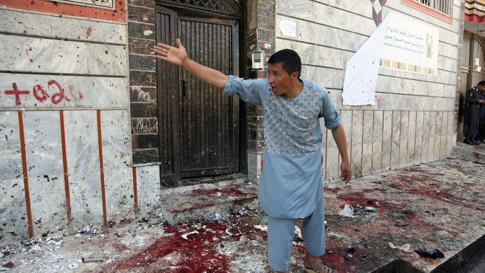 Afgánsky muž gestikuluje smerom ku policajtom po teroristickom útoku v Kábule.