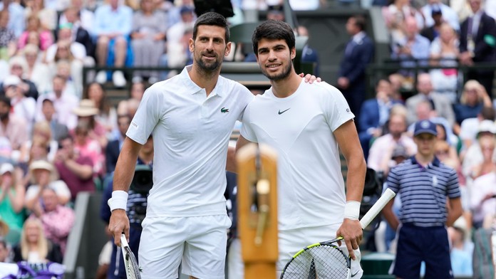 Novak Djokovič (vľavo) a Španiel Carlos Alcaraz pózujú pri sieti pred začiatkom finále mužskej dvojhry na grandslamovom tenisovom turnaji Wimbledon