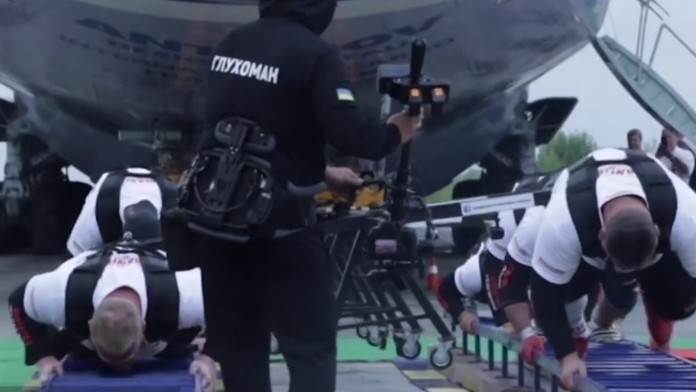 Siláci ťahajú lietadlo.