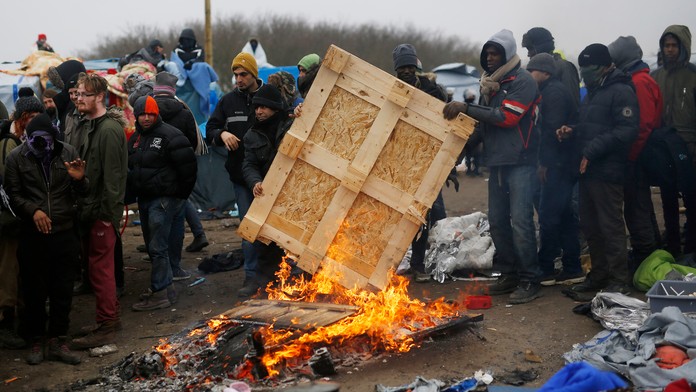 Migranti v tábore pri Calais protestujú na strechách búd.