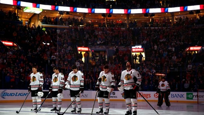 Hráč Chicaga Blackhawks Marián Hossa (vľavo) so spoluhráčmi si uctili obete piatkových teroristických útokov v Paríži pred zápas