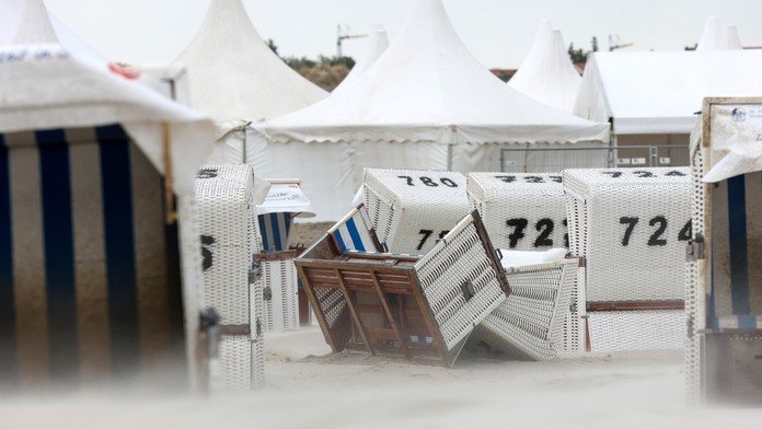 Piesok sa prevalil cez prevrátené plážové kreslá počas búrky v Sankt Peter Ordingu v severnom Nemecku.