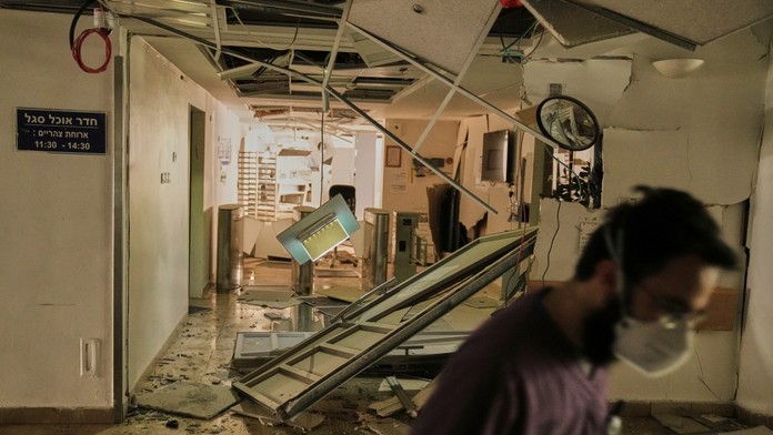 Zdravotník kráča vnútri zničenej časti nemocnice po raketovom útoku z Iránu.