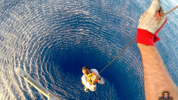 Pomocou lana zachraňujú z mora migranta v Stredozemnom mori medzi Líbyou a Talianskom. 12. augusta