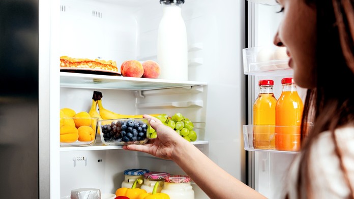 Žena ukladá do chladničky čučoriedky.