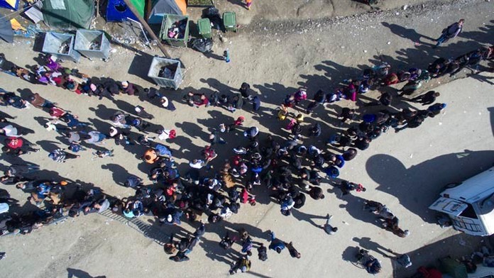 Migranti čakajú v rade na jedlo distribuované mimovládnymi organizáciami v utečeneckom tábore pri severogréckej dedine Idomeni n