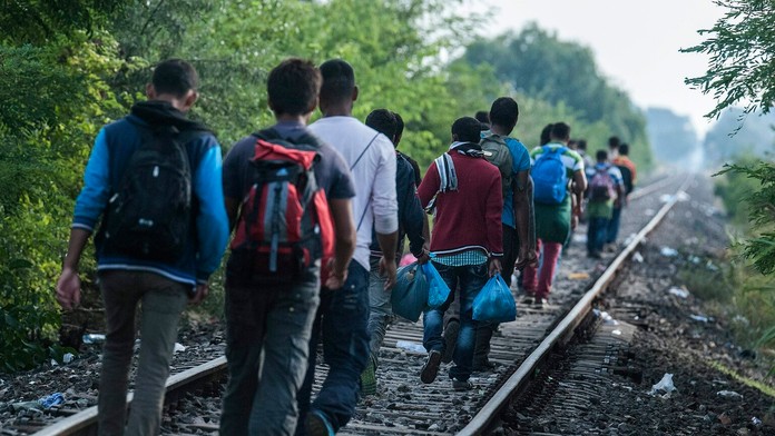 Utečenci prechádzajú po železničnej trati na maďarsko-srbských hraniciach