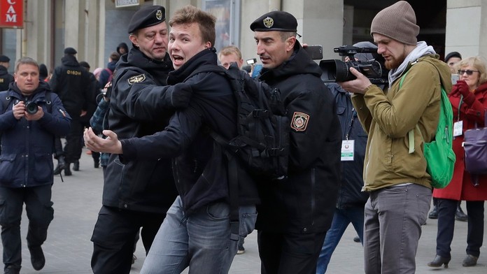 Policajti zatýkajú novinára Romana Protaseviča.