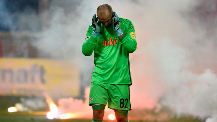 Brankár Slovana Ján Mucha si zapcháva uši po tom, čo priestor pred jeho bránkou zahádzali fanúšikovia Slovana pyrotechnikou.