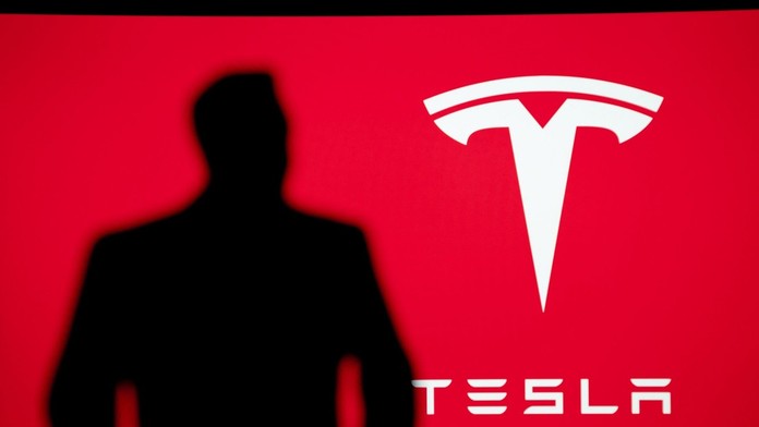 Na snímke logo Tesly a silueta Elona Muska.