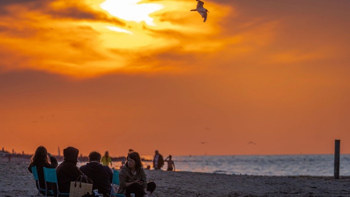 Ľudia sedia na pláži. 