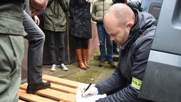 Na snímke policajt preberá balíky účtovníctva
