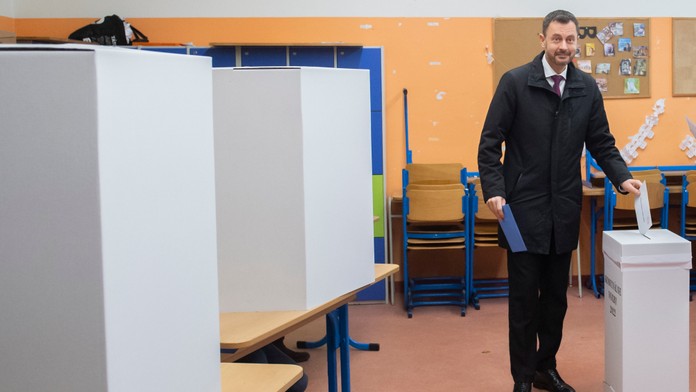 Premiér Eduard Heger vhadzuje obálku s hlasovacími lístkami do volebnej schránky pre komunálne voľby.