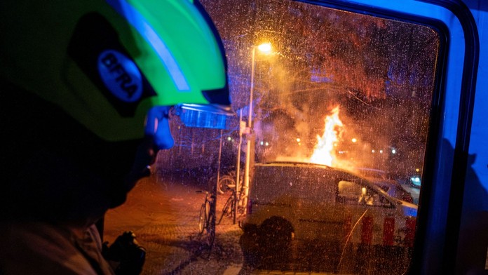 Na snímke hasič a horiace auto.