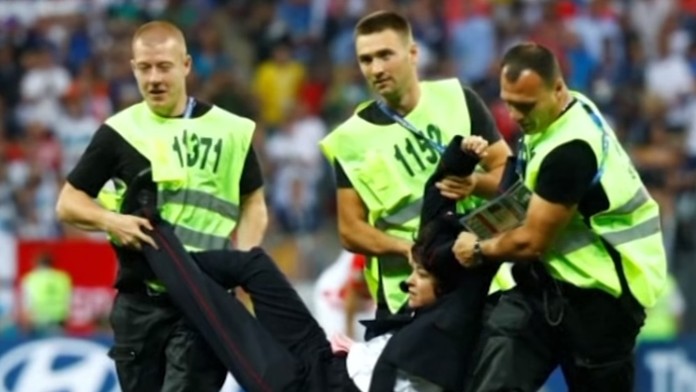 Usporiadateľská služba odnáša z ihriska aktivistku.