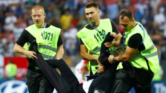 Usporiadateľská služba odnáša z ihriska aktivistku.