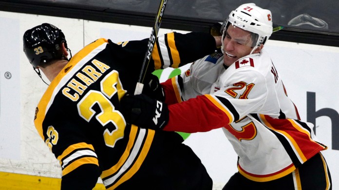 Jaroslav Halák z Bostonu chytá puk pred Michaelom Frolíkom z Calgary.