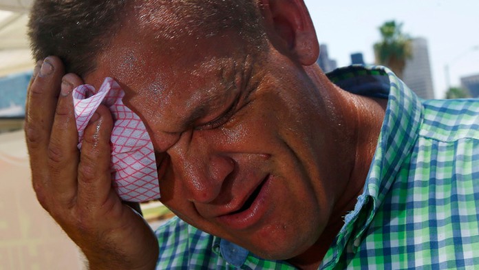 Muž si utiera z tváre pot.