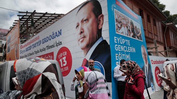 Ľudia kráčajú okolo plagátu s portrétom tureckého prezidenta Recepa Tayyipa Erdogana.