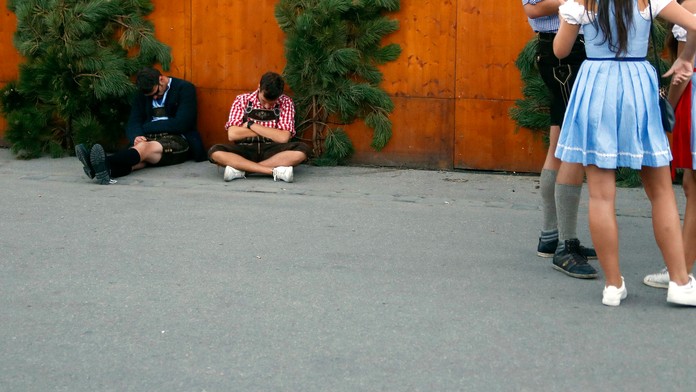 Dvaja návštevníci Oktoberfest "odpočívajú" na zemi.