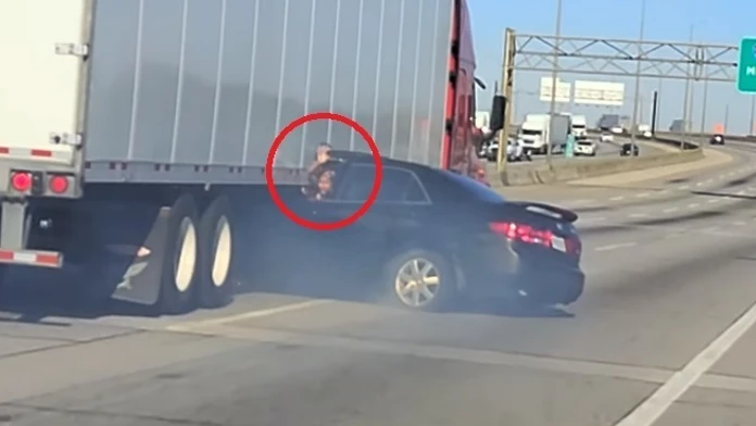 Žena volá o pomoc z auta zakliesneného pod kamiónom.