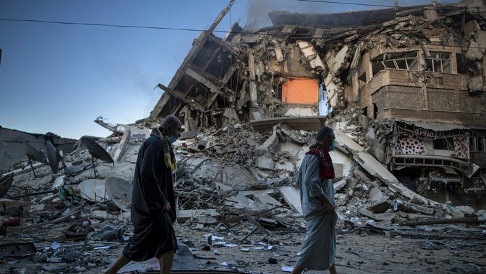 Ľudia kráčajú okolo zničenej budovy po izraelskom leteckom útoku pásme Gazy.