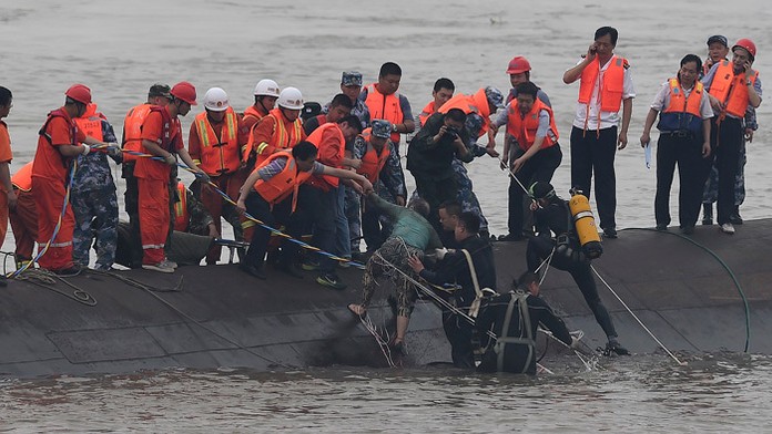 Na snímke záchranári vyťahujú z vody pasažiera (v strede) z lode, ktorá sa prevrátila na rieke Jang-c'-ťiang.