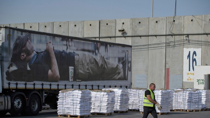 Pracovník kráča okolo nákladného auta s humanitárnou pomocou pre Pásmo Gazy.