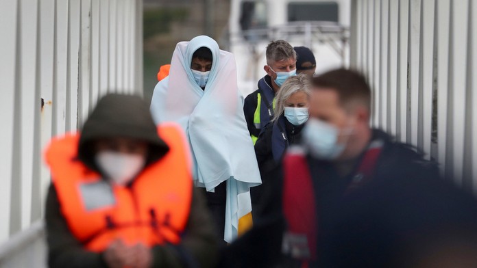 Skupina migrantov je eskortovaná policajtmi do prístavu v anglickom meste Dover.