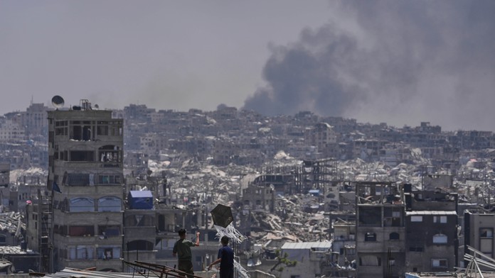 Palestínčania sa pozerajú ako dym stúpa pri explózii po izraelskom bombardovaní Pásma Gazy.