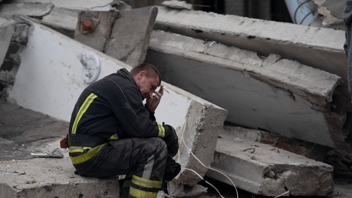 Záchranár sedí na mieste, kde našli mŕtvu ženu po ruskom útoku v obci Mykolajivka.